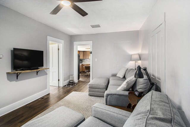 living area featuring ceiling fan, wood finished floors, visible vents, and baseboards