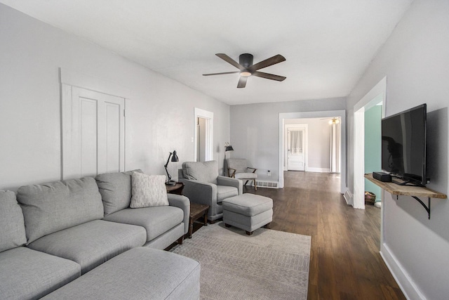 living room with dark wood-style floors, baseboards, and ceiling fan