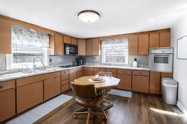 kitchen featuring a sink, dark wood-style floors, black microwave, light countertops, and stainless steel oven