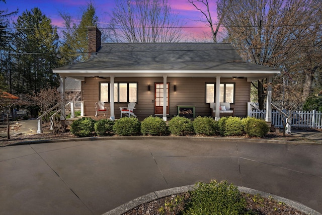 view of front of house with a ceiling fan, covered porch, and a chimney