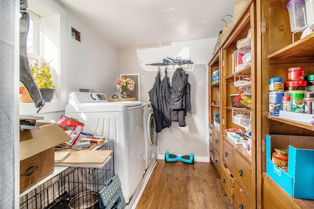 clothes washing area featuring washer and clothes dryer, laundry area, baseboards, and wood finished floors