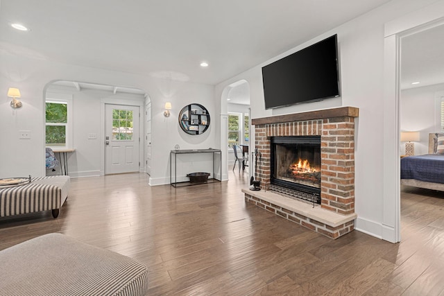 living room with a wealth of natural light, a brick fireplace, baseboards, and wood finished floors