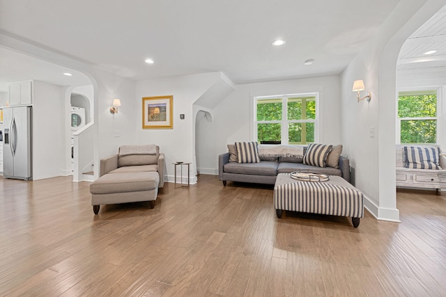 living room featuring arched walkways, light wood-style floors, and a healthy amount of sunlight
