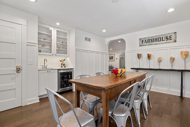 dining area with wine cooler, a decorative wall, arched walkways, and visible vents