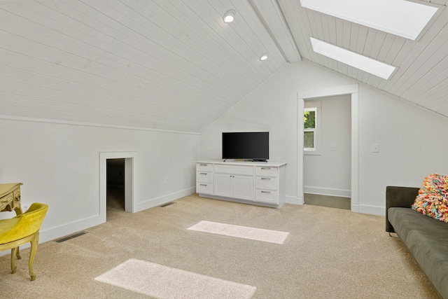 living room with visible vents, vaulted ceiling with skylight, light colored carpet, and baseboards