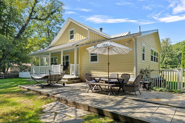 rear view of property with fence, a porch, metal roof, a yard, and a patio area