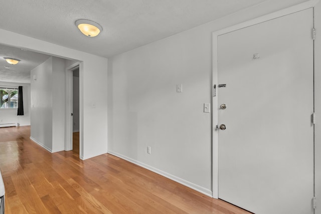 603 Gott St, Ann Arbor, MI 48103 - spare room with a baseboard heating unit, light wood-style flooring, baseboards, and a textured ceiling