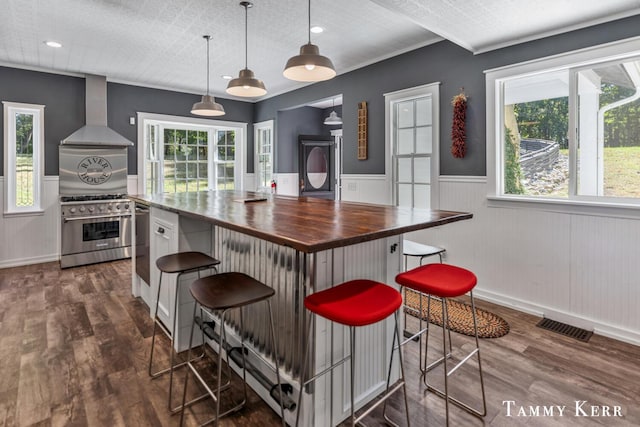 kitchen featuring visible vents, wooden counters, appliances with stainless steel finishes, wall chimney exhaust hood, and dark wood-style flooring