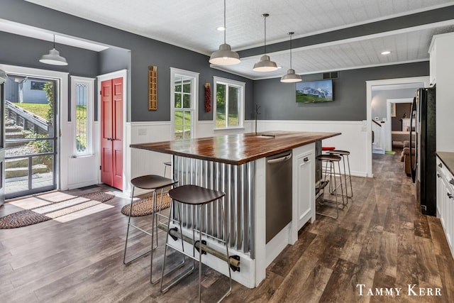 kitchen featuring a breakfast bar, freestanding refrigerator, white cabinets, wainscoting, and butcher block counters