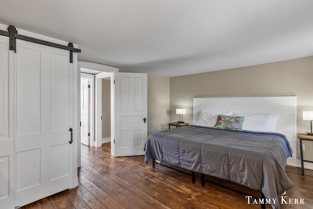 bedroom featuring a barn door and dark wood-style flooring