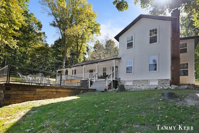 back of property featuring a lawn, a porch, and a chimney