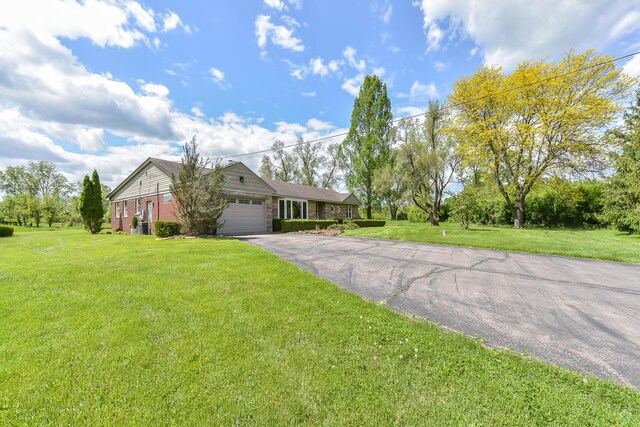 ranch-style home featuring aphalt driveway, a front lawn, and a garage