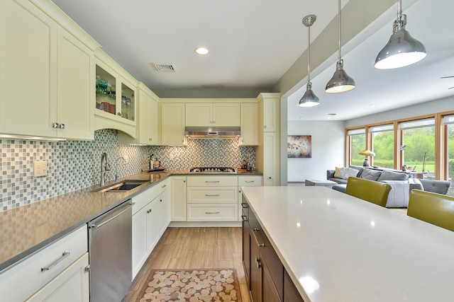 kitchen with visible vents, under cabinet range hood, open floor plan, appliances with stainless steel finishes, and a sink