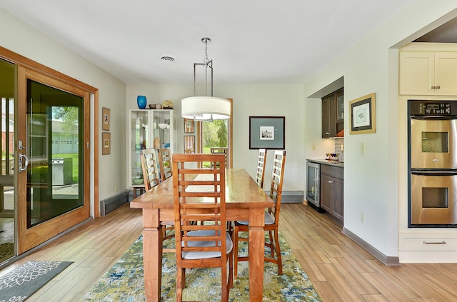 dining space featuring wine cooler, visible vents, baseboards, and light wood-style floors