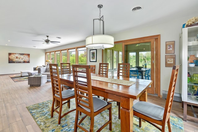 dining room with a ceiling fan, visible vents, baseboard heating, and light wood-type flooring