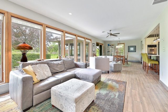 living room featuring visible vents, a healthy amount of sunlight, light wood-style flooring, and a ceiling fan