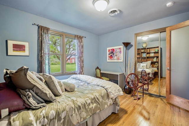 bedroom with light wood-style floors and visible vents