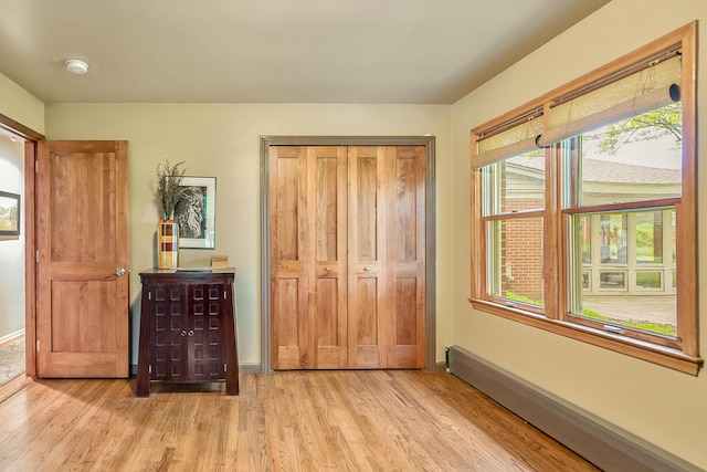 bedroom with light wood finished floors, baseboards, and a baseboard radiator