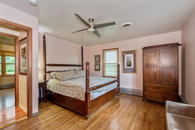 bedroom featuring light wood-type flooring, visible vents, baseboards, and ceiling fan