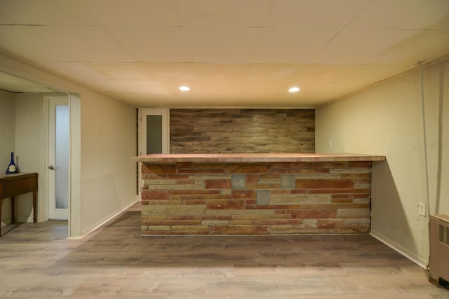 bar featuring recessed lighting, a bar, baseboards, and wood finished floors