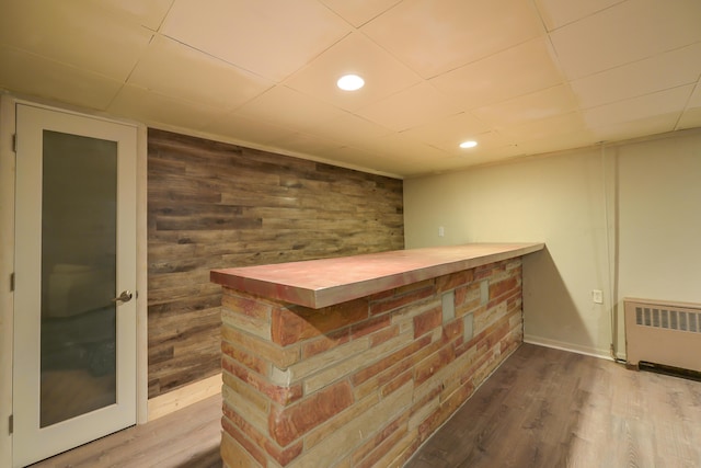 bar featuring wooden walls, recessed lighting, radiator, and wood finished floors