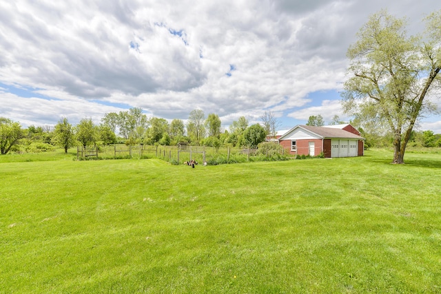 view of yard featuring a rural view, an outdoor structure, an attached garage, and fence