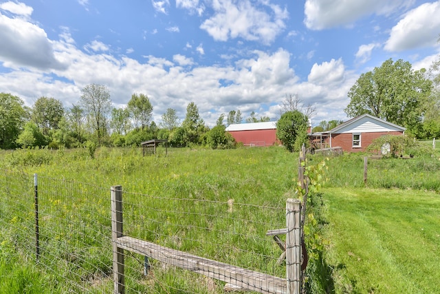 view of yard featuring a rural view, an outbuilding, a pole building, and fence