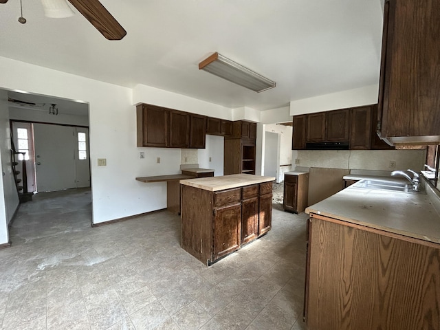 kitchen with dark brown cabinets, light floors, a ceiling fan, and a sink