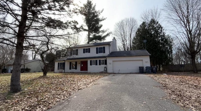 traditional-style house with an attached garage, driveway, and a chimney