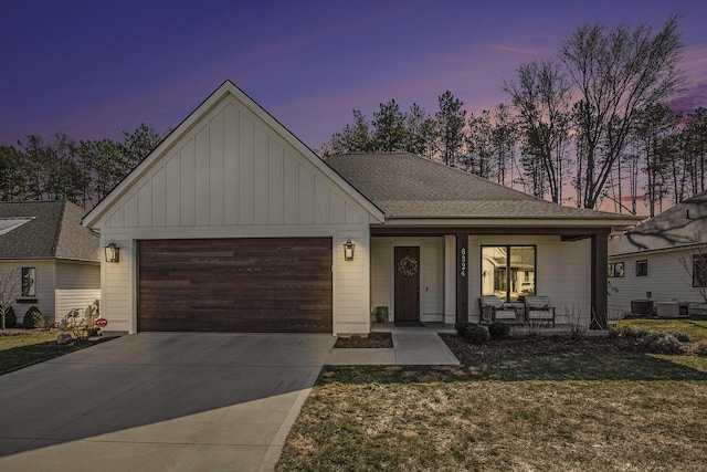 view of front facade featuring central air condition unit, concrete driveway, covered porch, a yard, and a garage