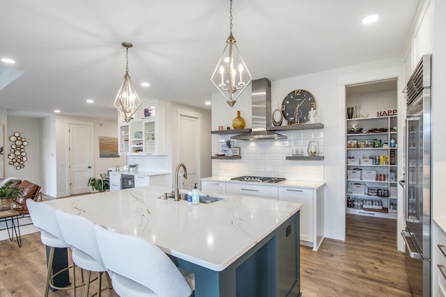 kitchen featuring light wood finished floors, open shelves, a sink, white cabinets, and wall chimney exhaust hood