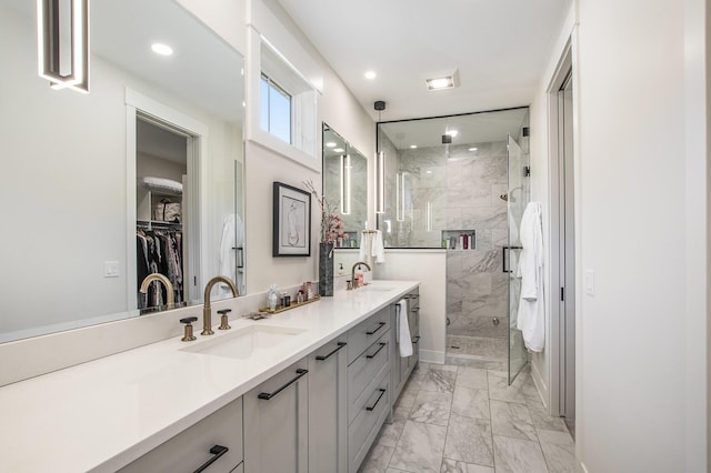 full bathroom featuring a sink, marble finish floor, a shower stall, and double vanity