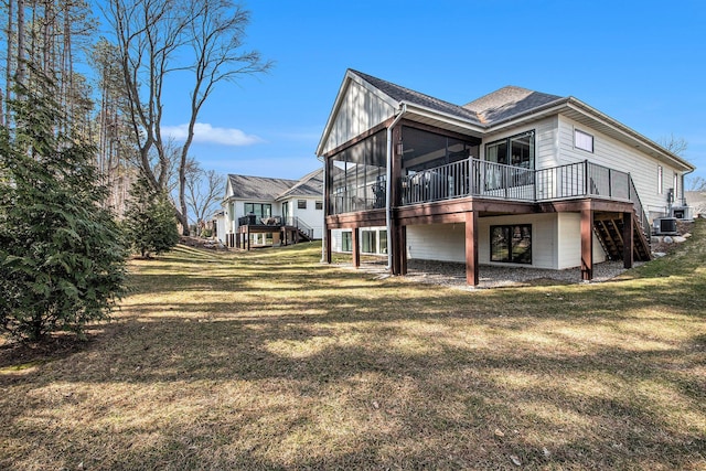 back of property featuring stairway, a yard, a sunroom, and a wooden deck