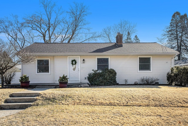 ranch-style house with a front lawn, roof with shingles, and a chimney