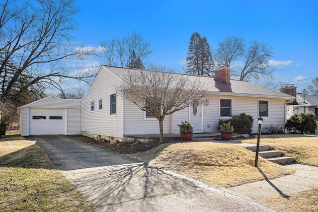 view of front facade with aphalt driveway, a chimney, a detached garage, and a front yard