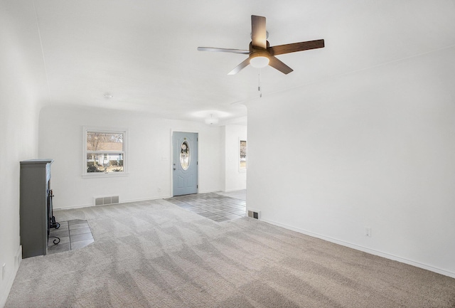 unfurnished living room featuring carpet flooring, a ceiling fan, visible vents, and baseboards