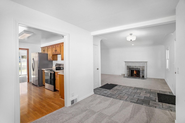 living area with visible vents, a fireplace with flush hearth, and light carpet