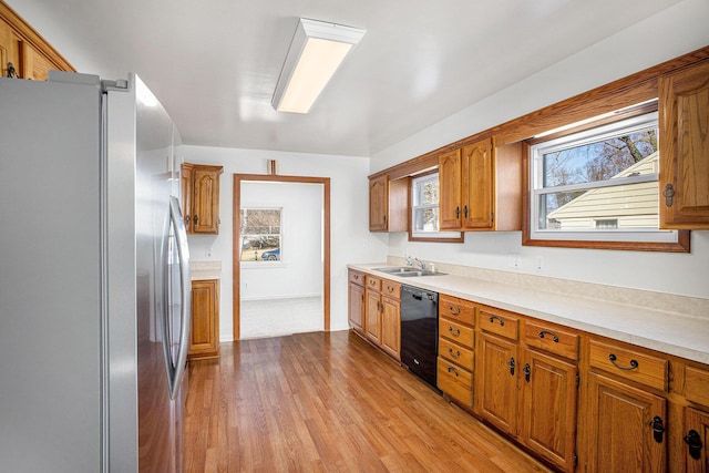 kitchen featuring a sink, plenty of natural light, black dishwasher, and freestanding refrigerator