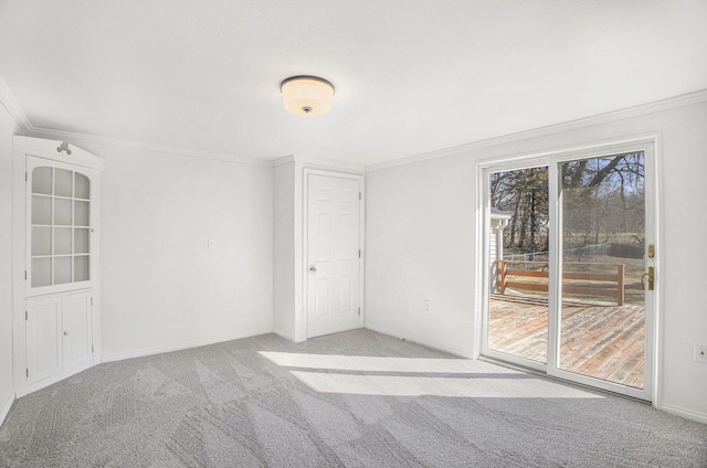 empty room featuring crown molding, carpet flooring, and baseboards