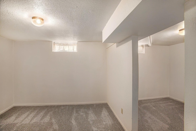 basement featuring baseboards, carpet, and a textured ceiling