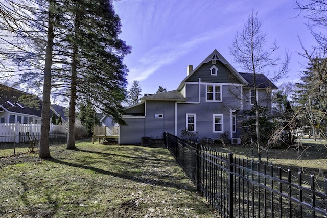exterior space with a lawn, a chimney, a deck, and a fenced backyard