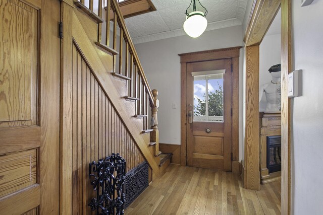 interior space with stairs, wood walls, light wood-style flooring, and an ornate ceiling