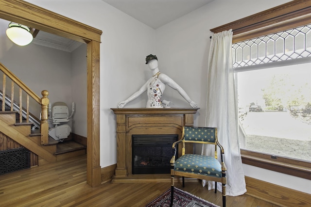 sitting room featuring a glass covered fireplace, wood finished floors, baseboards, and stairs