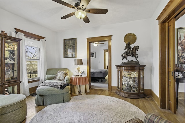 living area featuring baseboards, wood finished floors, and ceiling fan