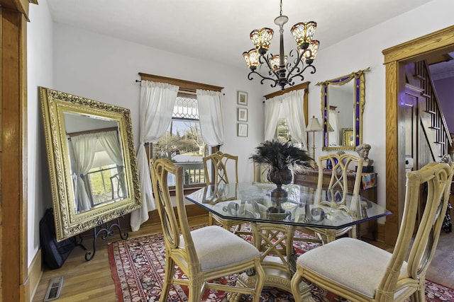 dining room featuring a chandelier, visible vents, wood finished floors, and baseboards