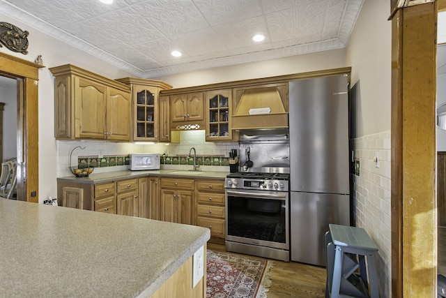 kitchen featuring glass insert cabinets, a sink, appliances with stainless steel finishes, dark wood-style floors, and an ornate ceiling
