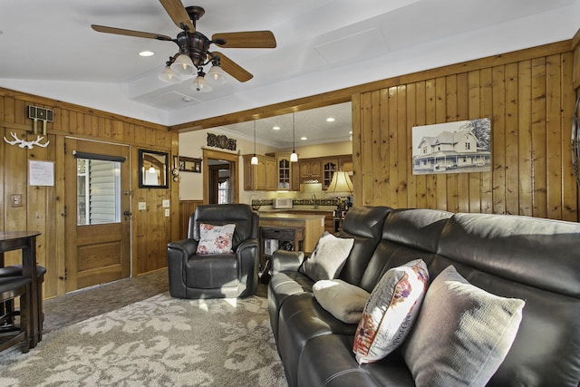 carpeted living area featuring crown molding, a sink, a healthy amount of sunlight, wooden walls, and a ceiling fan