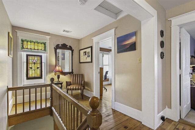 hallway with baseboards, visible vents, and wood-type flooring