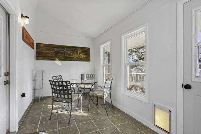 dining area featuring lofted ceiling, dark tile patterned floors, and baseboards