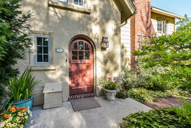 doorway to property with a chimney and stucco siding